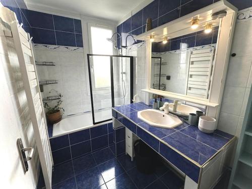 a blue tiled bathroom with a sink and a mirror at Superbe, 3 chambres, au calme, parkings in Décines-Charpieu