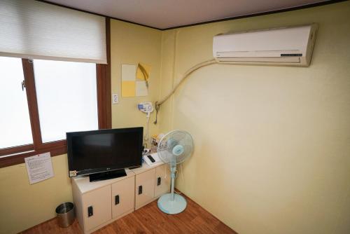 a room with a air conditioner and a television and a fan at Suncheon Namu Guesthouse in Suncheon