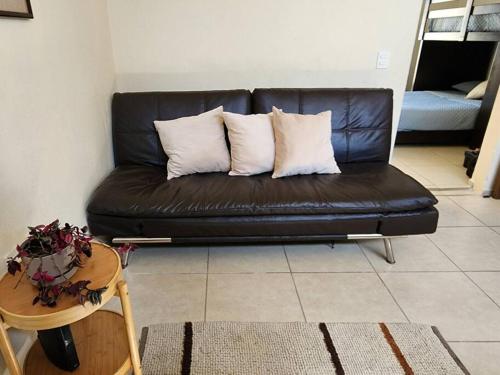 a black leather couch in a living room with a table at Casa para grupos grandes por el ITESO in Guadalajara