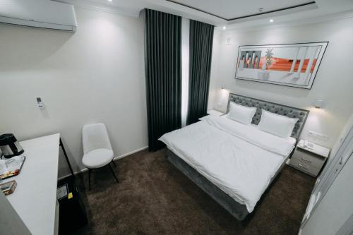 a hotel room with a white bed and a chair at Central Plaza Hotel in Urganch