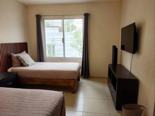 a room with two beds and a television and a window at Casa para grupos grandes por el ITESO in Guadalajara