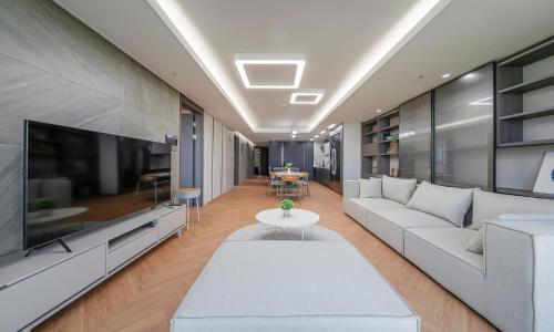 a living room with a white couch and a large tv at Busan Station BOOKING THE BAY in Busan