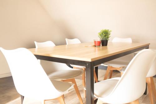 une table en bois entourée de chaises blanches dans l'établissement CENTRAL 55m2 - 4 PERSONNES - COSY - PROCHE NAUSICAA, à Boulogne-sur-Mer