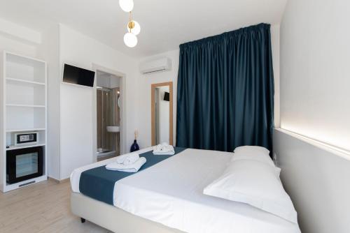 a bedroom with a white bed and a blue curtain at Room 86 in San Vito lo Capo