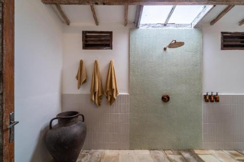 a bathroom with a glass shower with a vase at Akasia Villas in Gili Air