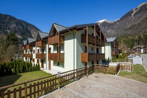 a building with a fence next to a mountain at Residence Rta La Rosa delle Dolomiti in Carisolo