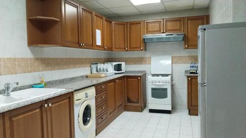 uma cozinha com armários de madeira e um aparelho branco em Al Massa Hotel Apartments 1 em Al Ain