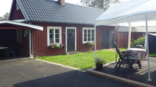 ein rotes Haus mit einem Tisch und einem weißen Zelt in der Unterkunft Bergsvägen Bed & Breakfast in Urshult