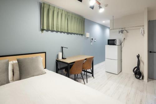 a bedroom with a bed and a table and a refrigerator at ARM ikebukuro in Tokyo