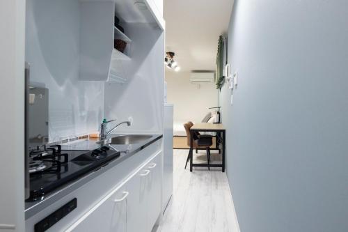 a white kitchen with a sink and a table at ARM ikebukuro in Tokyo