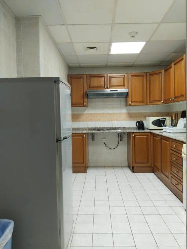 a kitchen with wooden cabinets and a refrigerator at Al Massa Hotel Apartments 1 in Al Ain