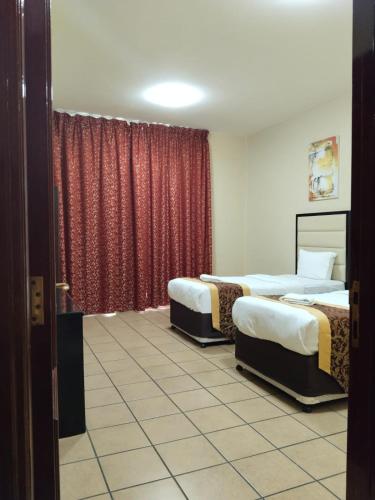 a room with two beds and a red curtain at Al Massa Hotel Apartments 1 in Al Ain