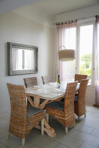 - une salle à manger avec une table et des chaises en osier dans l'établissement Duplex en Rooftop vue mer à la Salis, à Antibes