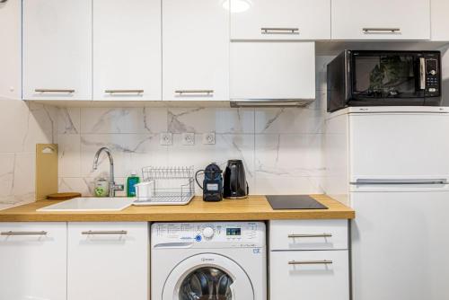 une cuisine blanche avec une machine à laver et un micro-ondes dans l'établissement GuestReady - Bel appartement cosy dans le 3e arr., à Paris