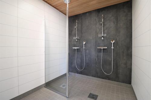 a shower stall in a bathroom with white tiles at Forenom Serviced Apartments Kirkkonummi in Helsinki