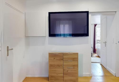 Elle comprend une télévision à écran plat suspendue sur un mur blanc. dans l'établissement Charmant Appartement 1 Chambre - Nation, à Paris