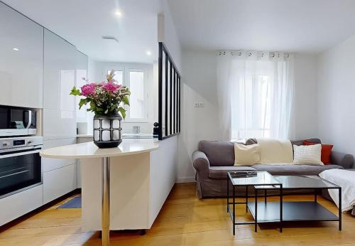 un salon avec un canapé et une table avec des fleurs dans l'établissement Charmant Appartement 1 Chambre - Nation, à Paris