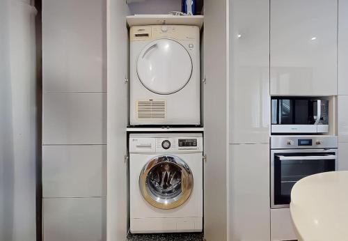 une cuisine avec un lave-linge et un micro-ondes dans l'établissement Charmant Appartement 1 Chambre - Nation, à Paris
