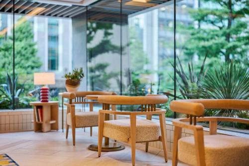 a row of chairs and tables in a room with windows at The Royal Park Hotel Ginza 6-Chome in Tokyo