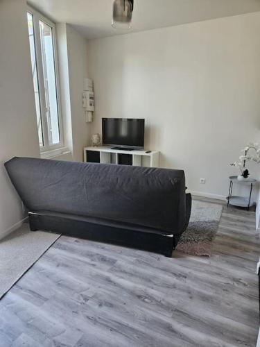 a black couch in a living room with a television at Beautiful F2 apartment 5 stops by train from Paris in Moret-sur-Loing