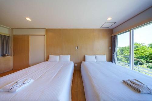 two beds sitting in a room with a window at クリスタルヴィラ南城 in Azama