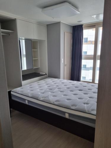 ein großes Bett in einem Zimmer mit Fenster in der Unterkunft Sokcho Koaroo Arista in Sokcho