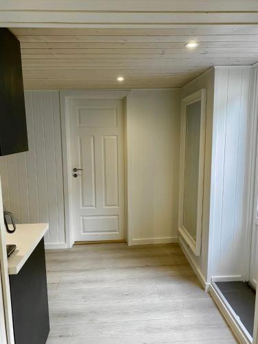 an empty room with a white door and wooden floors at Down town apartment with outside area in villa in Kristiansand