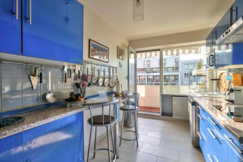 une cuisine avec des placards bleus et des tabourets de bar dans l'établissement GuestReady - 105m2 bright apartment, à Paris