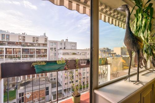 un oiseau debout sur un balcon avec vue sur une ville dans l'établissement GuestReady - 105m2 bright apartment, à Paris