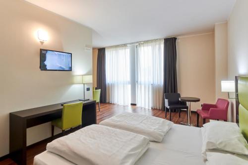 Cette chambre comprend deux lits, un bureau et des chaises. dans l'établissement Kona Hotel Verona, à Negrar