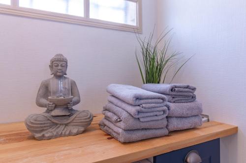 une statue de Bouddha assis sur une étagère avec des serviettes dans l'établissement La joie de vivre: logement entier, parking privé, à Sainte-Savine