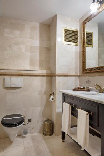 a bathroom with a toilet and a sink and a mirror at Chatto Hotel in Tuzla