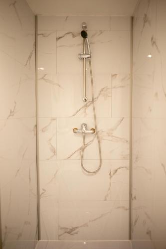 d'une douche avec des murs en marbre blanc et un pommeau de douche. dans l'établissement Cocon avec spa dans le centre, à Boulogne-sur-Mer