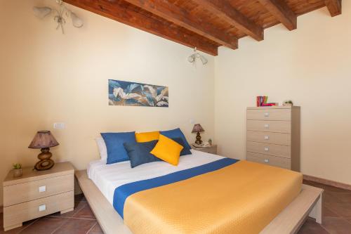 a bedroom with a bed with blue and yellow pillows at Sant'Antioco - Spazioso appartamento al centro in SantʼAntìoco