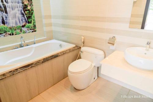 une salle de bain avec toilettes, lavabo et baignoire dans l'établissement Villa A16 Bách Thanh view hồ - Đại Lải resort, à Phúc Yên