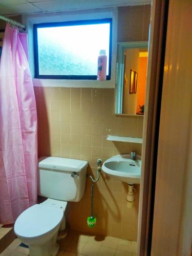 a bathroom with a toilet and a sink and a window at Cozy & Comfy 3 rooms apartment near beach in Batu Ferringhi