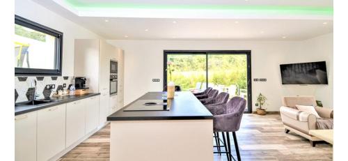 une cuisine avec des placards blancs et un bar avec des chaises dans l'établissement Jolie villa avec piscine sans vis a vis, à Bezouce