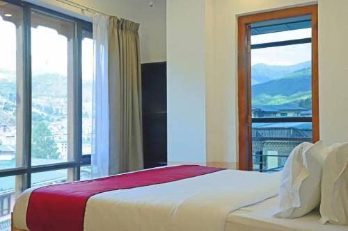 a bedroom with a bed and a large window at The BD Hotel in Thimphu