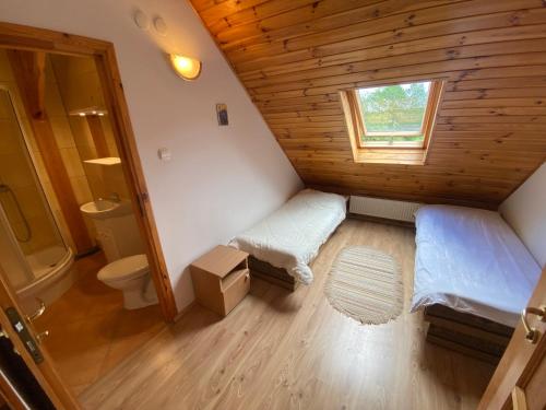 a small attic bedroom with a bed and a toilet at Zabytkowa Karczma in Jedwabno