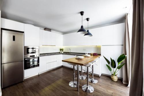 uma cozinha com armários brancos e uma mesa de madeira em Apartamentos Turísticos Metropolis em Cartagena