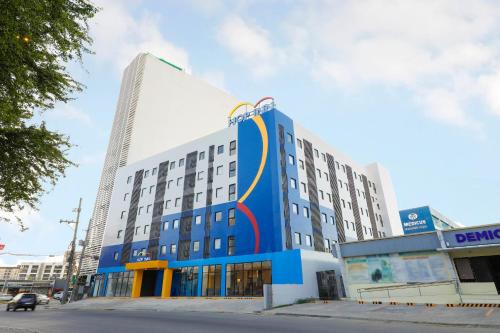 a blue and white building with a tall building at Hop Inn Hotel Iloilo in Iloilo City