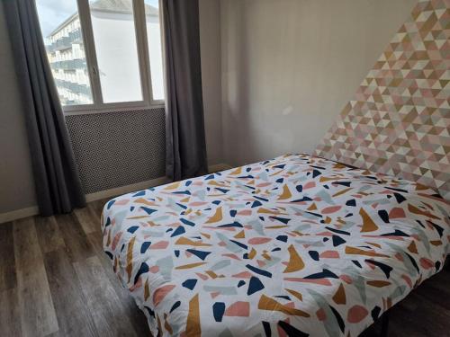 une chambre avec un lit avec une couette colorée dans l'établissement Refuge Urbain Chic avec Balcon, à Saint Lo