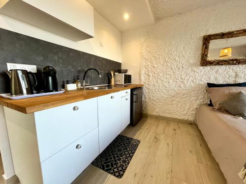 - une cuisine avec des placards blancs et un lavabo dans la chambre dans l'établissement Joli studio vue mer avec terrasse et jardinet à Sant Ambroggio, à Lumio