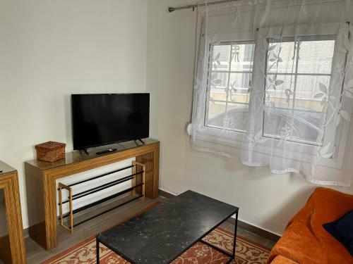 a living room with a flat screen tv and a window at Cosy new apartment in Néa Michanióna