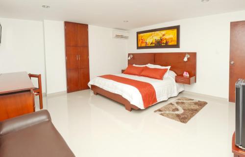 a bedroom with a bed and a desk and a television at Hotel Andino in Bucaramanga