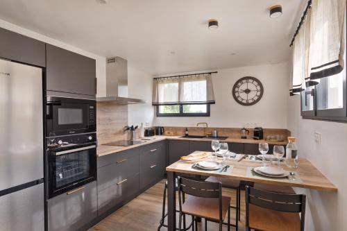 une cuisine avec une table et une horloge au mur dans l'établissement The Blue Rocks - Maison à moins d'1 km de la plage, à Lamballe