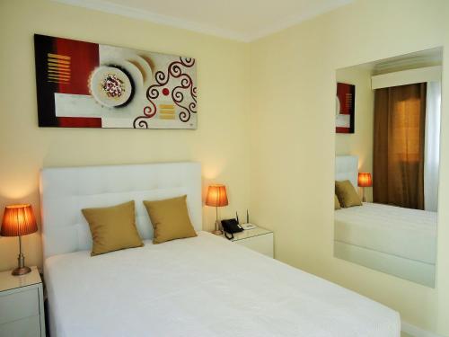 een slaapkamer met een wit bed en een spiegel bij São Francisco Accommodation in Funchal