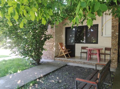 a patio with a table and chairs under a tree at Ananuri Cottages in Ananuri