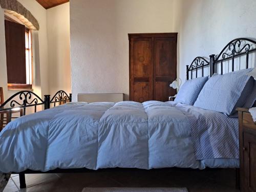 a bedroom with a bed with blue sheets and a wooden door at B&B S'Omu Antiga in Nureci