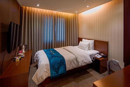 a small hotel room with a bed and a desk at Namsan Hill Hotel in Seoul
